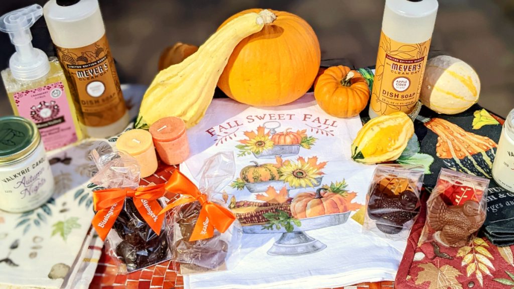 Fall-themed home decor including dish towel, scented dish soaps, gourds, candles, and chocolate turkeys.